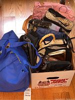 Top view showing variety of purses including blue tote and multiple handbags in a box with different colors and fabrics.