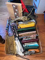 Photo of assortment of purses, wallets, clutches, and wristlets arranged in a cardboard box, showing variety of styles and colors