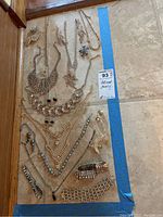 Full view of assorted rhinestone necklaces, earrings, pins, and bracelets laid out on floor.