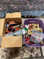 Box and purple bin with assorted vintage toy vehicles, track pieces, plastic playset parts, and loose action figures.