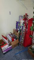 Photo showing various gift wrapping paper rolls standing upright alongside gift bags and boxes