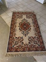 Rectangular oriental pattern area rug laid out on floor showing central medallion and fringe edges