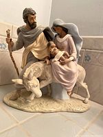 Side angled view of ceramic Holy Family statue showing Mary seated holding Baby Jesus on donkey and Joseph standing beside with staff.
