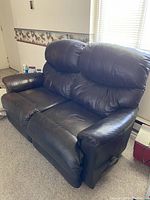 Photo showing brown leather loveseat with plush cushions and visible side recline lever, both seats appear to recline and rock.