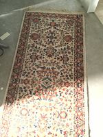 Top-down photo showing full length of the rectangular oriental runner rug with floral and vine patterns.