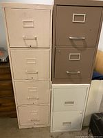 Three metal filing cabinets grouped together, one with four drawers and two with two drawers each.