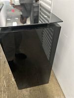 Close-up image showing one glass shelf with polished edges and black tinted base/support underneath. Reflection visible on base.