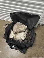 Open black storage bag showing heavy duty metal tire chains and a worn white packaging bag labeled Road Blazer Tire Chains with tire sizes and company info.