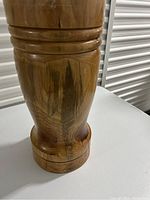 Close-up side view of tall wooden planter showing carved rings and wood grain