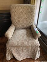 Front view of vintage high back armchair with damask pattern upholstery, showing the seat cushion, rolled arms, and skirted bottom.