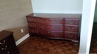 Front view of wood dresser showing six drawers and decorative brass hardware