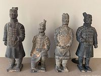 Four terracotta warrior statues in a row showing variety of poses and detailed armor work.