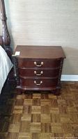 Front view of Hickory White wood nightstand with three drawers and brass handles, showing carved details on the sides and curved drawer fronts.