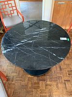 Top-down view of round black marble tabletop with white veining.