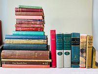 Stacked books showing colorful spines with various titles, some worn or faded