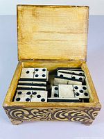 Open box showing old dominoes neatly arranged inside.