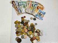 Photo showing coins and banknotes spread out on a white surface, highlighting the variety and condition of the items.