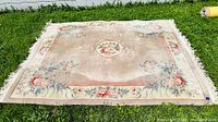 Photo of the full vintage Chinese Peking carpet laid on grass, showing the Art Deco floral design and central medallion.