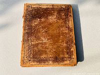 Front cover of the leather bound book showing wear and decorative tooling.