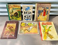 Top view of six antique children's books displayed on a surface showing colorful illustrated covers with various story themes.