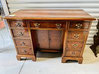 Front view showing nine drawers, central cabinet door, brass hardware