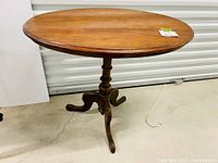 Full view of oval mahogany occasional table on tripod wooden legs, showing overall shape and finish.