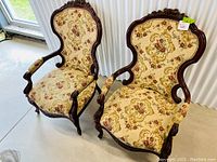 Front view of both chairs side by side showing matching upholstery and carved frames