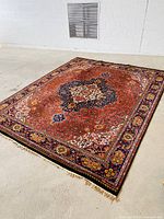 Full view of carpet showing red ground, central medallion and fringes