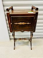 Front view of antique walnut smoking stand with humidor-style compartment door and turned handle, showing top surface and base
