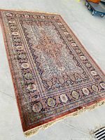 Full view of rectangular rug on concrete floor showing overall pattern and fringe