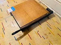 Photo trimming board with cast iron cutter and wooden base on patterned surface