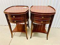 Pair of mahogany circular bedside cabinets shown side by side, featuring two drawers and lower triangular shelf each.