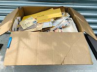 Large cardboard box filled with hundreds of postal covers and first day covers, showing the quantity and mixed sizes.