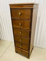 Full front view of tallboy chest showing six carved drawer fronts and brass knobs