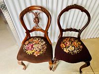 Front view of both chairs showing carved backs and needlepoint seats