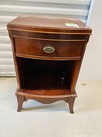 Front view of vintage French walnut nightstand showing one drawer with oval handle and open shelf below