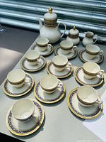 Group photo of entire coffee/tea set including coffee pot, sugar bowl, creamer, cups, and saucers arranged on table.