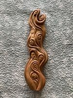Top-down view of the hand-carved wooden sculpture showing several human faces and flowing shapes in integrated design.