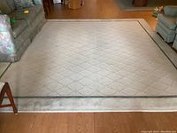 Full view of off-white rug with diamond lattice pattern laid on hardwood floor