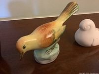 Side view of the hand-painted Herend bird on a greenish base.