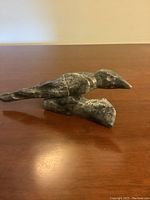 Side view of soapstone bird carving showing the detailed bird shape on its base with engraved feather design