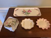 Lot of four porcelain pieces on a wooden surface showing floral patterns and shape details