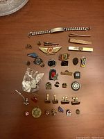 Full display of pins, tie clips, bracelet, and cufflinks on a wooden surface.