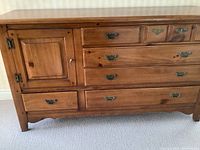 Front view of solid pine wood dresser showing drawers, cabinet door, and metal handles.