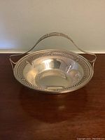 Front angled view of the sterling silver basket bowl showing polished interior and decorative pierced border with handle
