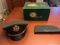Two vintage U.S. military hats placed alongside original Top Rank Service Corp green box on wood table