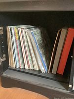 Photo showing a collection of approximately 30-40 vintage vinyl records upright on a shelf with visible album spines.