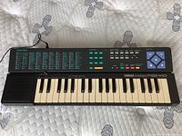 Full view of Yamaha PortaSound PSS-140 keyboard showing layout of keys, speaker, and control buttons on quilted surface.