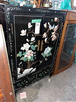 Full frontal view of the black lacquered wood cabinet with painted floral and bird garden scene on doors and drawer front.