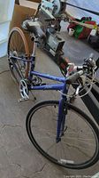 Left side view of blue Bontrager bike showing front wheel with tire, drop handlebars, and chainrings.